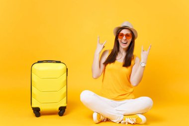 Mutlu turist kadın yaz rahat kıyafetler, çanta, şapka sit boynuzları üzerinde sarı turuncu arka plan izole jest. Hafta sonu kaçış üzerinde seyahat için yurt kız. Hava uçuş kavramı