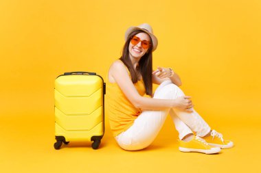 Seyahat etmek turist kadın yaz rahat kıyafetler, sarı turuncu arka plan üzerinde izole çanta şapka sit. Hafta sonu kaçış üzerinde seyahat için yurt kadın yolcu. Hava yolculuğu kavramı