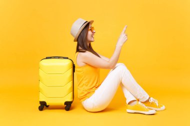 Seyahat etmek turist kadın yaz rahat kıyafetler, sarı turuncu arka plan üzerinde izole çanta şapka sit. Hafta sonu kaçış üzerinde seyahat için yurt kadın yolcu. Hava yolculuğu kavramı