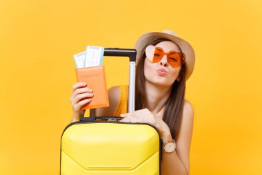 Eğlenceli turist kadın yaz rahat kıyafetler, şapka, çanta, sarı zemin üzerine izole pasaport turuncu güneş gözlüğü. Hafta sonu kaçış üzerinde seyahat için yurt dışında seyahat yolcu. Hava uçuş kavramı