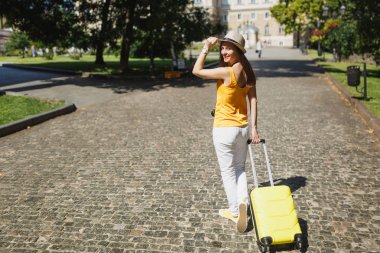 Geri dikiz gezgin turist kadın rahat kıyafetler çanta şehirde açık yürüyüş etrafında seyir şapka el tutmak. Hafta sonu kaçamağı yurt kız. Turizm yolculuk yaşam tarzı