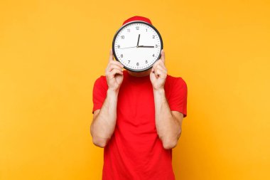 Teslimatçı sarı turuncu arka plan üzerinde izole kırmızı üniforma. Profesyonel gülümseyen erkek çalışan şapkalı, kurye veya satıcı holding olarak boş t-shirt çalışma saat yuvarlak. Hizmet anlayışı.