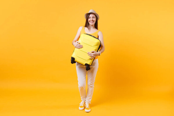 Traveler tourist woman in summer casual clothes, hat with suitcase isolated on yellow orange background. Female passenger traveling abroad to travel on weekends getaway. Air flight journey concept