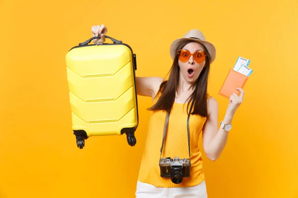 Seyahat etmek turist kadın yaz rahat kıyafetler, bavul, sarı turuncu arka plan üzerinde izole passport bileti ile şapka. Hafta sonu kaçış üzerinde yurt dışı seyahat seyahat kız. Hava uçuş yolculuk kavramı.