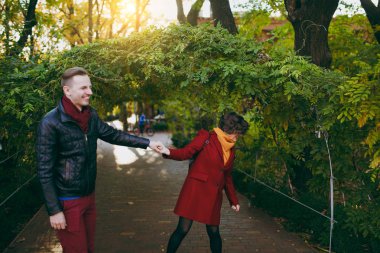 Yeşil kemer sonbahar Şehir Parkı yakınındaki yolda gülüyor kadın ve adam tarafından yürüyüş rahat sıcak giysiler içinde aşık genç mutlu çift, açık havada güneşli bir günde eller. Aşk ilişki aile yaşam tarzı kavramı