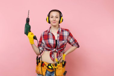 Enerji seksi tamirci kadın eldiven, gürültü yalıtımlı kulaklıklar, Seti Araçları, pembe arka plan izole elektrikli matkap tutan araçların tam kemer. Kadın erkek iş. Yenileme kavramı