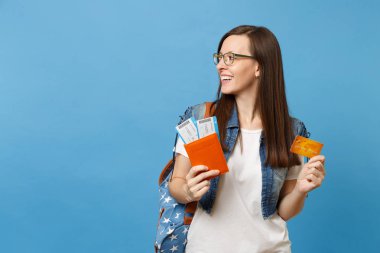 Sırt çantası arıyorum ile genç güzel kadın öğrenci bir kenara pasaport yatılı pas bilet kredi üzerinde mavi arka plan izole kart tutun. Yurt dışındaki üniversiteler eğitim. Hava seyahat uçuş kavramı