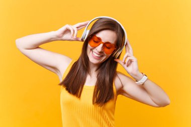 Turuncu gözlük üzerinde sarı arka plan izole kulaklık kopya alanı içinde müzik dinlemek sakin gülümseyen genç kadın portresi. İnsanlar samimi duygular, yaşam kavramı. Reklam alanı. Geri kalan sakin ol