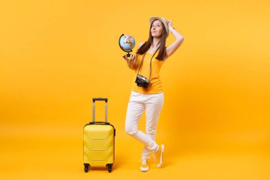 Seyahat etmek turist kadın yaz rahat kıyafetler, küre, sarı turuncu arka plan üzerinde izole bavul ile şapka. Hafta sonu kaçış üzerinde seyahat için yurt dışında seyahat yolcu. Hava uçuş yolculuk kavramı