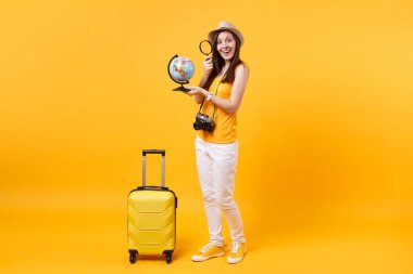 Seyahat etmek turist kadın yaz rahat kıyafetler, küre, sarı turuncu arka plan üzerinde izole bavul ile şapka. Hafta sonu kaçış üzerinde seyahat için yurt dışında seyahat yolcu. Hava uçuş yolculuk kavramı