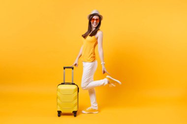 Seyahat etmek turist kadın yaz rahat kıyafetler, sarı turuncu arka plan üzerinde izole çanta şapka. Hafta sonu kaçış üzerinde seyahat için yurt kadın yolcu. Hava uçuş yolculuk kavramı