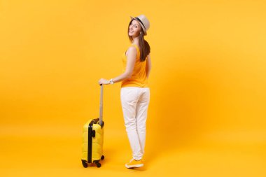 Arkadan görünüm turist kadın yaz rahat kıyafetler, sarı turuncu arka plan üzerinde izole çanta şapka. Hafta sonu kaçış üzerinde seyahat için yurt kadın yolcu. Hava uçuş yolculuk kavramı