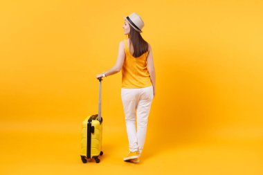 Arkadan görünüm turist kadın yaz rahat kıyafetler, sarı turuncu arka plan üzerinde izole çanta şapka. Hafta sonu kaçış üzerinde seyahat için yurt kadın yolcu. Hava uçuş yolculuk kavramı