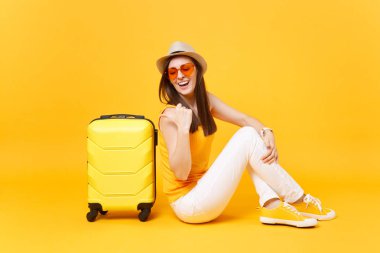 Seyahat etmek turist kadın yaz rahat kıyafetler, sarı turuncu arka plan üzerinde izole çanta şapka sit. Hafta sonu kaçış üzerinde seyahat için yurt kadın yolcu. Hava yolculuğu kavramı