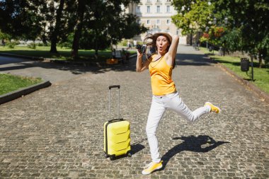 Komik hayran gezgin turist kadın çanta başına tutunmuş şapkalı şehirde açık atlama retro vintage fotoğraf kamera tutun. Hafta sonu kaçamağı yurt kız. Turizm yolculuk yaşam tarzı