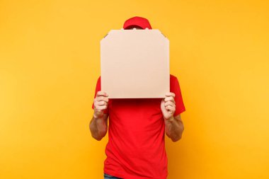 Kırmızı şapka, tişört veren yemek sipariş pizza kutuları üzerinde sarı arka plan izole teslimat adam. Erkek çalışan pizzaman kurye pizza boş boş karton flatbox kopya alanı içinde tutarak. Hizmet anlayışı