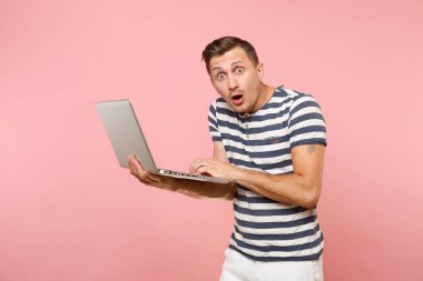 Dizüstü bilgisayarda, kopya alanı çalışma çizgili tişört konsantre genç adam portresi pastel pembe arka plan eğilimleri izole. İnsanlar samimi duygular yaşam tarzı kavramı. Reklam alanı