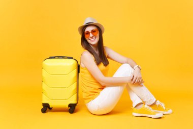Seyahat etmek turist kadın yaz rahat kıyafetler, sarı turuncu arka plan üzerinde izole çanta şapka sit. Hafta sonu kaçış üzerinde seyahat için yurt kadın yolcu. Hava yolculuğu kavramı