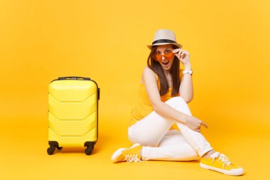 Seyahat etmek turist kadın yaz rahat kıyafetler, sarı turuncu arka plan üzerinde izole çanta şapka sit. Hafta sonu kaçış üzerinde seyahat için yurt kadın yolcu. Hava yolculuğu kavramı