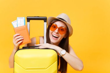 Eğlenceli turist kadın yaz rahat kıyafetler, şapka, çanta, sarı zemin üzerine izole pasaport turuncu güneş gözlüğü. Hafta sonu kaçış üzerinde seyahat için yurt dışında seyahat yolcu. Hava uçuş kavramı