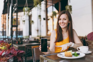 Açık havada sokak kahve kadında bardak çay ile masada oturan Cafe shop, kek, elinde boş boş ekran, rahatlatıcı restoranda serbest zaman sırasında cep telefonuyla tutun. Yaşam tarzı dinlenme kavramı