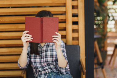 Restoranda serbest zaman sırasında rahatlatıcı ile Kupası kokteyl, kitap okuma açık havada sokak yaz kahve dükkanı ahşap kafe rahat kıyafetler içinde oturan güzel kadın. Yaşam tarzı dinlenme tatil kavramı