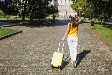 Dikiz seyahat etmek turist kadın sarı yaz rahat kıyafetler şapkalı şehirde açık bavul dönüyoruz. Hafta sonu kaçış üzerinde seyahat için yurt kız. Turizm yolculuk yaşam tarzı kavramı