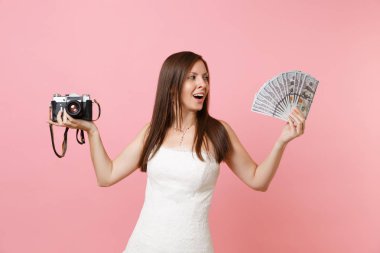 Heyecanlı gelin düğün elbise holding retro vintage fotoğraf makinesi, kadında çok dolar, nakit para seçerek personel, fotoğrafçı, pembe arka plan izole paket. Yapılacaklar listesi düğün organizasyonu,