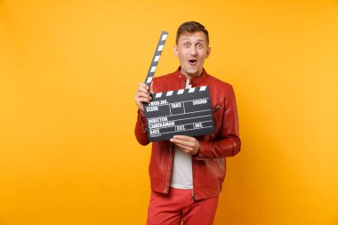 Deri ceket, t-shirt Klaket yapma klasik kara film tutan genç adam gülümseyen portre vogue parlak sarı eğilimleri arka plan üzerinde izole. İnsanlar yaşam tarzı kavramı. Reklam alanı
