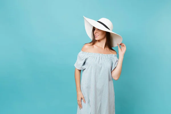 优雅时尚的画像美丽的年轻女子在白色夏天大宽边缘的太阳帽 礼服把手放在头上 看着旁边的拷贝空间孤立的蓝色粉彩背景 生活方式概念 — 图库照片