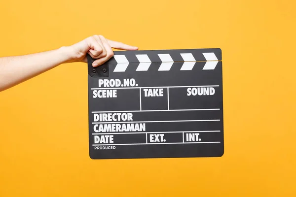 Close up female holding in hand classic director clear empty black film making clapperboard isolated on yellow orange background. Cinematography production concept. Copy space for advertising