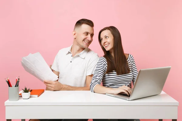 Two young tender business woman man colleagues sit work at white desk with contemporary laptop isolated on pastel pink background. Achievement career concept. Copy space advertising, youth co working
