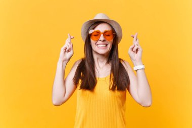 Özel bir an için bekliyor. Kadın turuncu gözlük parmak çarpı işareti tutmak ve gözler gülümseyen portresi kapalı. Yapma arzusu. Sarı arka plan üzerinde izole alanı kopyalayın. İnsanlar samimi duygular kavramı