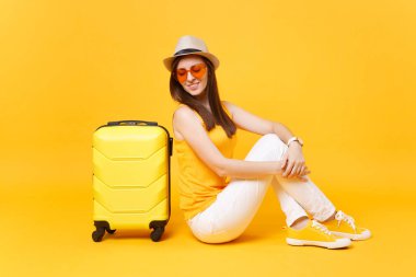 Seyahat etmek turist kadın yaz rahat kıyafetler, sarı turuncu arka plan üzerinde izole çanta şapka sit. Hafta sonu kaçış üzerinde seyahat için yurt kadın yolcu. Hava yolculuğu kavramı