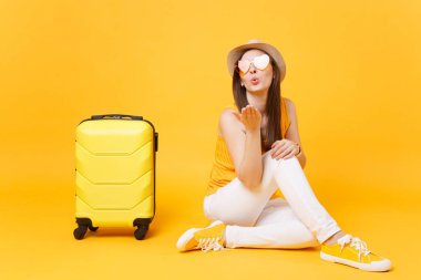 Seyahat etmek turist kadın yaz rahat kıyafetler, sarı turuncu arka plan üzerinde izole çanta şapka sit. Hafta sonu kaçış üzerinde seyahat için yurt kadın yolcu. Hava yolculuğu kavramı