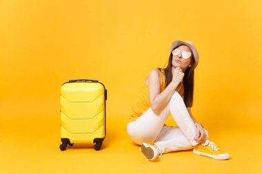 Seyahat etmek turist kadın yaz rahat kıyafetler, sarı turuncu arka plan üzerinde izole çanta şapka sit. Hafta sonu kaçış üzerinde seyahat için yurt kadın yolcu. Hava yolculuğu kavramı