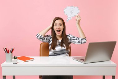 Heyecanlı kadın var yeni fikir, düşünce pastel pembe izole pc dizüstü bilgisayar ile beyaz masa başında Say bulut konuşma balonu ampul çalışma ile tutun. Başarı iş kariyer kavramı. Kopya alanı
