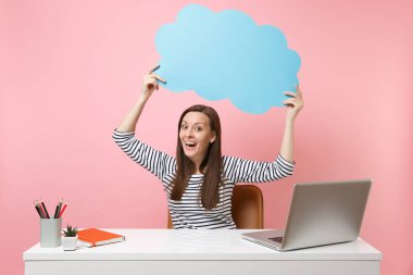Pastel pembe izole pc dizüstü bilgisayar ile beyaz masa başında mavi boş boş Say bulut konuşma balonu iş tutan heyecanlı kadın. Başarı iş kariyer kavramı. Kopya alanı reklam için