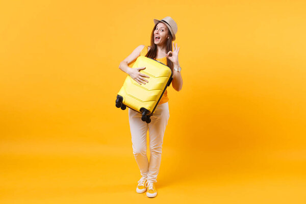 Traveler tourist woman in summer casual clothes, hat with suitcase isolated on yellow orange background. Female passenger traveling abroad to travel on weekends getaway. Air flight journey concept