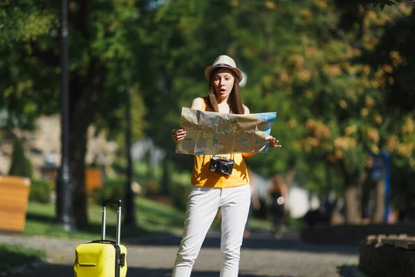 若い市屋外歩行のスーツケースの市内地図で黄色の夏私服帽子の旅行観光女に衝撃を与えた 週末の息抜きに旅行に海外旅行の女の子 観光旅ライフ スタイル — ストック写真