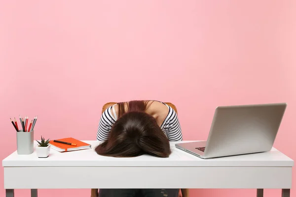 Genç sinir bozucu yorgun kadın kafasını masaya yatırdı, pastel pembe arka plan üzerinde izole çağdaş pc dizüstü bilgisayar ile beyaz masa başında iş otur. Başarı iş kariyer kavramı. Kopya alanı
