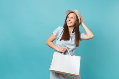 Portre sonra alışveriş izole mavi pastel arka plan üzerinde elbise, hasır şapka paketleri çanta ile tutarak satın alan yaz aylarında gülümseyen güzel beyaz kadın heyecan. Kopya alanı reklam için