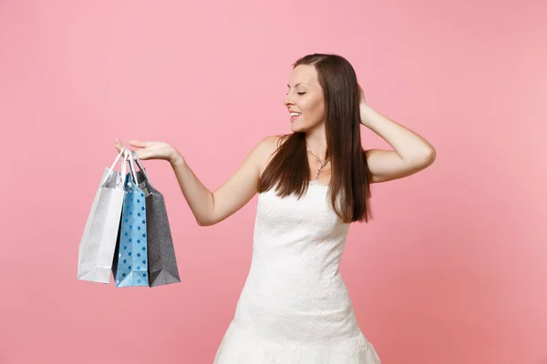 漂亮的新娘在婚纱礼服保持在头上寻找多色包装袋与购买后 在粉红色背景的购物 组织婚礼概念 复制空间 — 图库照片