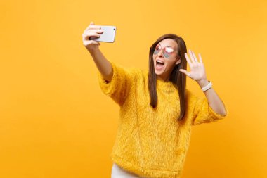Heyecanlı kadın kalp bardaklarda alarak selfie cep telefonu parlak sarı arka plan üzerinde izole tebrik için el sallayarak video görüşmesi atış yapıyor. İnsanlar samimi duygular, yaşam tarzı. Kopya alanı