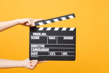 Sarı turuncu arka plan üzerinde izole Klaket yapma el klasik yönetmen temizleme boş siyah film tutan erkek kapatın. Sinematografi üretim kavramı. Kopya alanı reklam için
