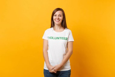 Mutlu gülümseyerek portresi beyaz t-shirt ile yazılı yazıt yeşil başlık gönüllü üzerinde sarı arka plan izole kadın memnun. Gönüllü ücretsiz destek yardım, sadaka grace iş kavramı