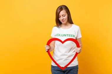 Beyaz kadın portresi t-shirt ile yazılı yazıt yeşil başlık gönüllü büyük kırmızı ahşap kalp üzerinde sarı arka plan izole tutun. Gönüllü ücretsiz destek yardım, sadaka grace iş kavramı
