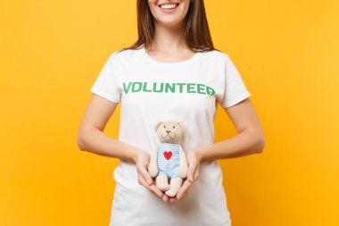 Beyaz kadın portresi t-shirt ile yazılı yazıt yeşil başlık gönüllü oyuncak ayı peluş oyuncak sarı arka plan üzerinde izole tutun. Gönüllü ücretsiz destek yardım, sadaka grace iş kavramı