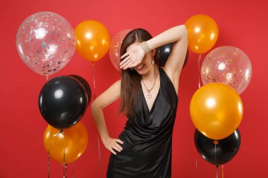 Küçük siyah elbise parlak kırmızı arka plan hava balonları Palm'da suratla kapsayan kutlayarak gülümseyen genç kız. St. Valentine's, kadınlar günü, mutlu yeni yıl, Doğum günü mockup tatil parti konsept