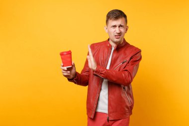 Vogue genç adam 25-30 yıl içinde kırmızı deri ceket, t-shirt Kupası Kahve izole üzerinde parlak sarı eğilimleri arka plan ile portresi. İnsanlar samimi duygular yaşam tarzı kavramı. Reklam alanı.